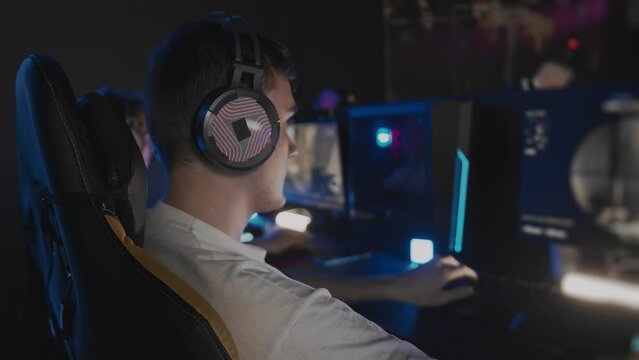 Caucasian teen gamer in headset playing PC video game at computer club. E-sport championship tournament, cyber sport team. Multiplayer online competition tactical first-person shooter