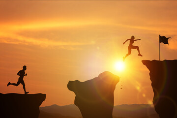 Effort and commitment to success. Silhouette of women and men competing jumping over a cliff to...