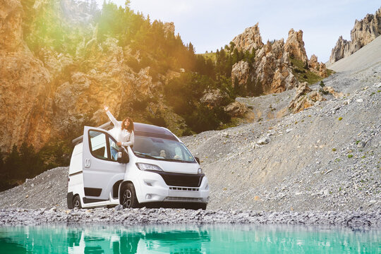 Road trip en camping car avec femme heureuse en vacances au bord d'un lac turquoise en &eacute;t&eacute; dans les montagnes
