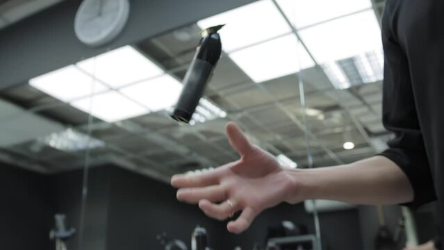 A man's hand rotates and flips a hair clipper in a hairdressing salon. The concept of modern stylish haircuts in a barbershop, close-up. Slow motion