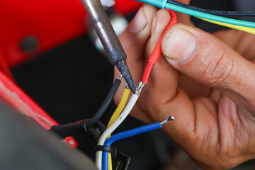 Fototapeta na wymiar selective focus wires in the hand of a car mechanic Practicing repairs to the ATV's electrical system. Wires of various colors help you know the direction of your car's electrical system.