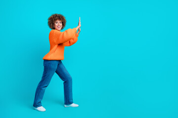 Full length profile photo of positive strong motivated woman pushing huge banner empty space isolated on blue color background