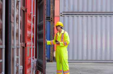 Portrait of Asian male worker wearing safety helmet and reflective vest opening container door for container inspection in freight cargo shipping yard - 748671363