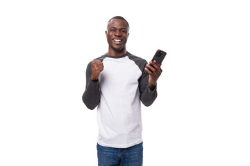 portrait of a young african man with a short haircut dressed casually and holding a smartphone in his hand