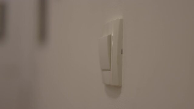Close up of woman left hand turning on light switch in the apartment 