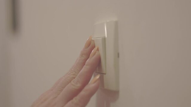 Close up shot of a woman hand turning light switch off