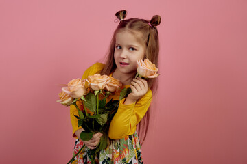 Obraz na płótnie Canvas Little smiling girl holding flowers on pink background. International women's day.