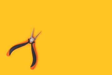 Round-nose pliers on a yellow background. Copy space for text. - obrazy, fototapety, plakaty