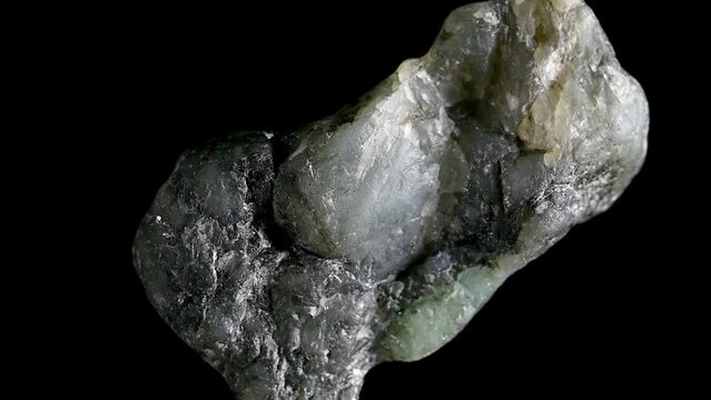 Raw Uncut Brazilian Emeralds sample rotating slowly against a black background.	