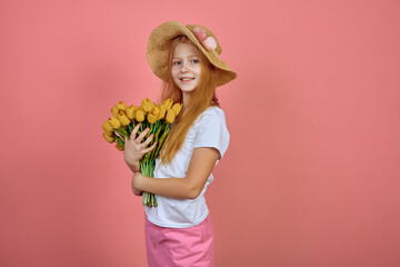 Teen redhead smiling girl with yellow tulips, flowers on pink background with hat. International women's day.