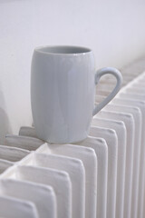 Fototapeta na wymiar White coffee cup on a white radiator