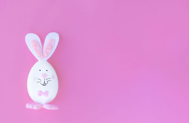 Easter egg, decorated in the shape of a bunny on a pink background with space for text, banner or greeting card with Happy Easter