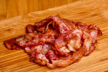 slices of fried bacon on a wooden board.