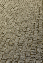 The texture of the paving slab (paving stones) of many small stones of a square shape under bright sunlight.