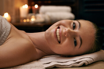 Happy, woman and portrait in spa with candles at night for luxury treatment in hotel on vacation. Girl, relax and smile on table for cosmetics, skincare and holiday at resort for beauty and wellness