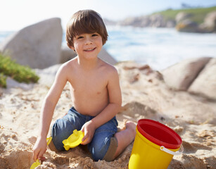 Sand castle, beach and portrait of child with bucket and toys on summer holiday, vacation and relax by ocean. Childhood, building sandcastle and young boy playing for adventure, fun or weekend by sea