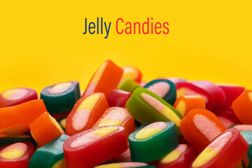 Piles of delicious colorful jelly candies on yellow background