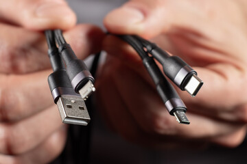 hands holding universal adapter cable from USB connector to micro USB, mini-USB and other connectors