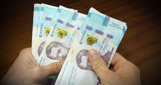 Cash counting. Man holds thousand hryvnia bills in his hands. Currency exchange. Hands holds banknotes. Converting cash Ukrainian money. New paper thousand hryvnia bills