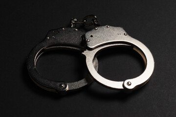 Shiny metal handcuffs on the dark table