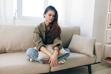 Fototapeta premium Lonely Woman, Stressed and Depressed, Sitting on Couch, Expressing Sadness and Worry, Feeling Pain in Mental Health.
