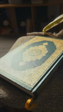 No people vertical footage of holy book Quran in dark green hard cover decorated with golden ornaments lying on coffee table at home