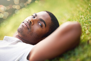 Portrait, serious and black man on grass in garden of summer park for peace, wellness or...
