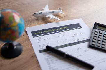 Selective focus image of travel insurance claim form on a wooden table. Travel, protection and insurance concept.