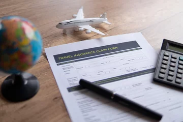 Tuinposter Selective focus image of travel insurance claim form on a wooden table. Travel, protection and insurance concept. © izzuan