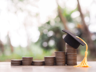 Graduation hat on stack of coins. The concept of saving money for education, student loan,...