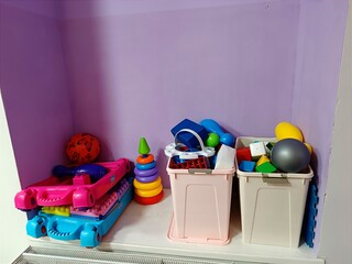 Kids toys sorted in plastic box, containers for toddler, kids, children. Empty children's playroom without anyone. Colorful construction, ball, pyramid, cube, block stand on windowsill. Kid zone
