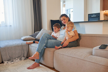 Woman with two little sons is at home on the sofa