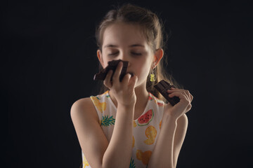 Beautiful little girl eating dark chocolate cocoa bar  - 748733348