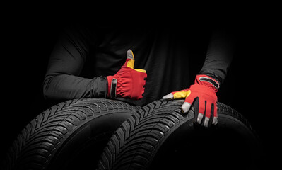 Car tire service and hands of mechanic holding new tyre on black background with copy space for text. - 748734173