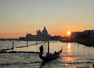 Fototapeta na wymiar Gondola at sunset in Venice, with Basilica della Salute in the background