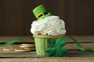 St. Patrick's day party. Tasty cupcake with green leprechaun hat topper on wooden table, closeup