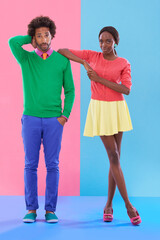 Confused, couple and portrait with fashion in studio, background and creative aesthetic. Doubt, question and woman with support of man and together with colorful retro style and unique clothes mockup