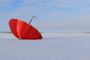 A colorful and vibrant red open umbrella with gold colored trim and handle sits upside down on...