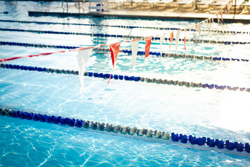 Shallow DOF string of colorful triangular backstroke flags hanging over public competitive swimming...