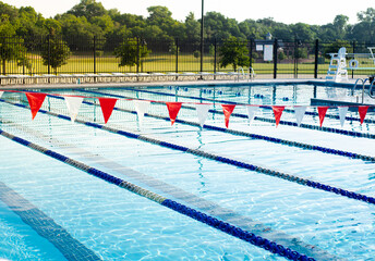 Public competitive swimming pool near large park, string of backstroke flag hanging over lane...