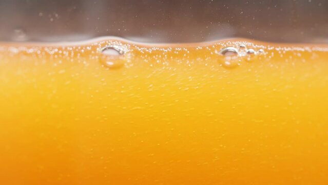 Orange Juice or Soda Macro Shot, Bubbles and Liquid Level in the Glass, Slow Motion.