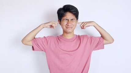 Asian man with a gesture covering his ears with his hands because of the noise