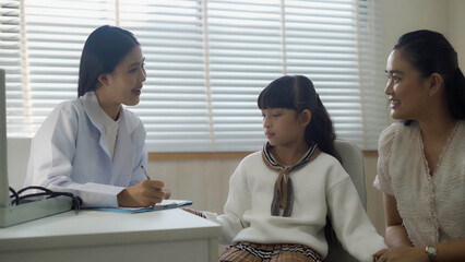 Female doctor examines sick girl's health and gives medical advice to her mother at a modern hospital Ready to give advice on case examination	