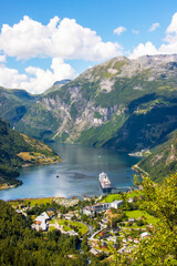 Fototapeta na wymiar Portrait view across the town of Geiranger and the Fjord with a cruise ship 