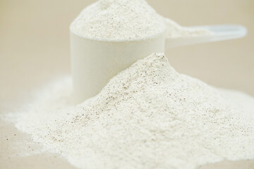 Close up of plant protein powder in plastic scoop. Whey protein powder background.