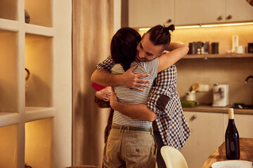Male and female friends in a hug, standing at home.