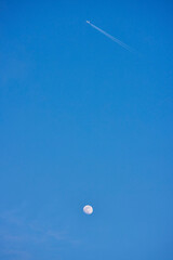 landscape with the moon and an airplane in the blue sky