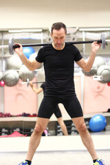 Middle aged man doing wide stance barbell squat in gym