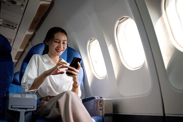 Smiling Asian woman enjoying a comfortable flight while sitting in an airplane cabin There is wireless internet on the plane. Passengers near the window