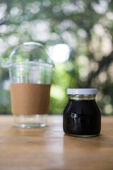 Cold coffee bottle and empty glass on the wooden table. Relaxing with iced coffee at home.